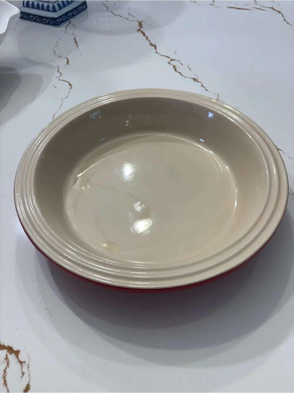 Le Creuset Cerise Red pie baking dish featuring a cream-colored interior.